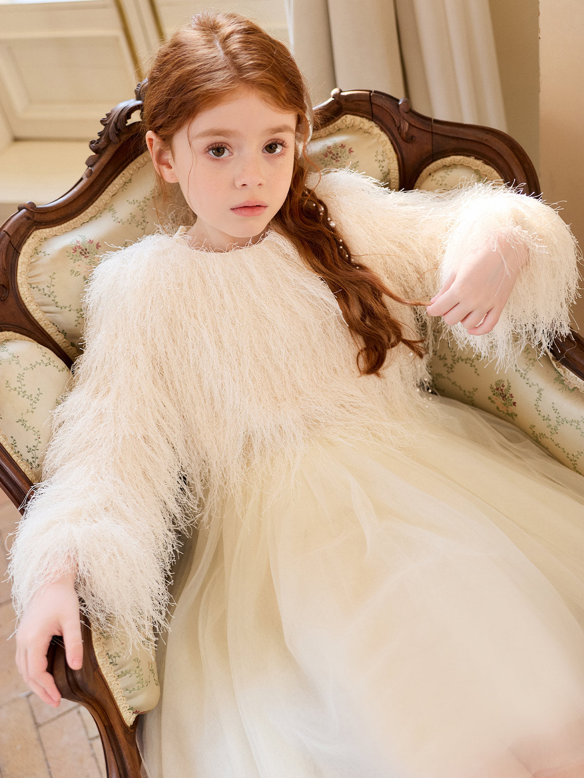 Seated model wearing the cream tulle dress with a textured cream outer layer