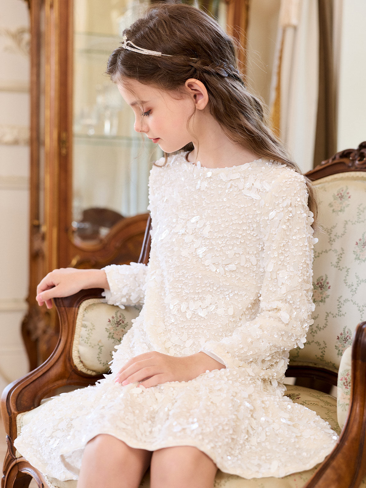Seated model showing the ivory sequin dress and flounce hem