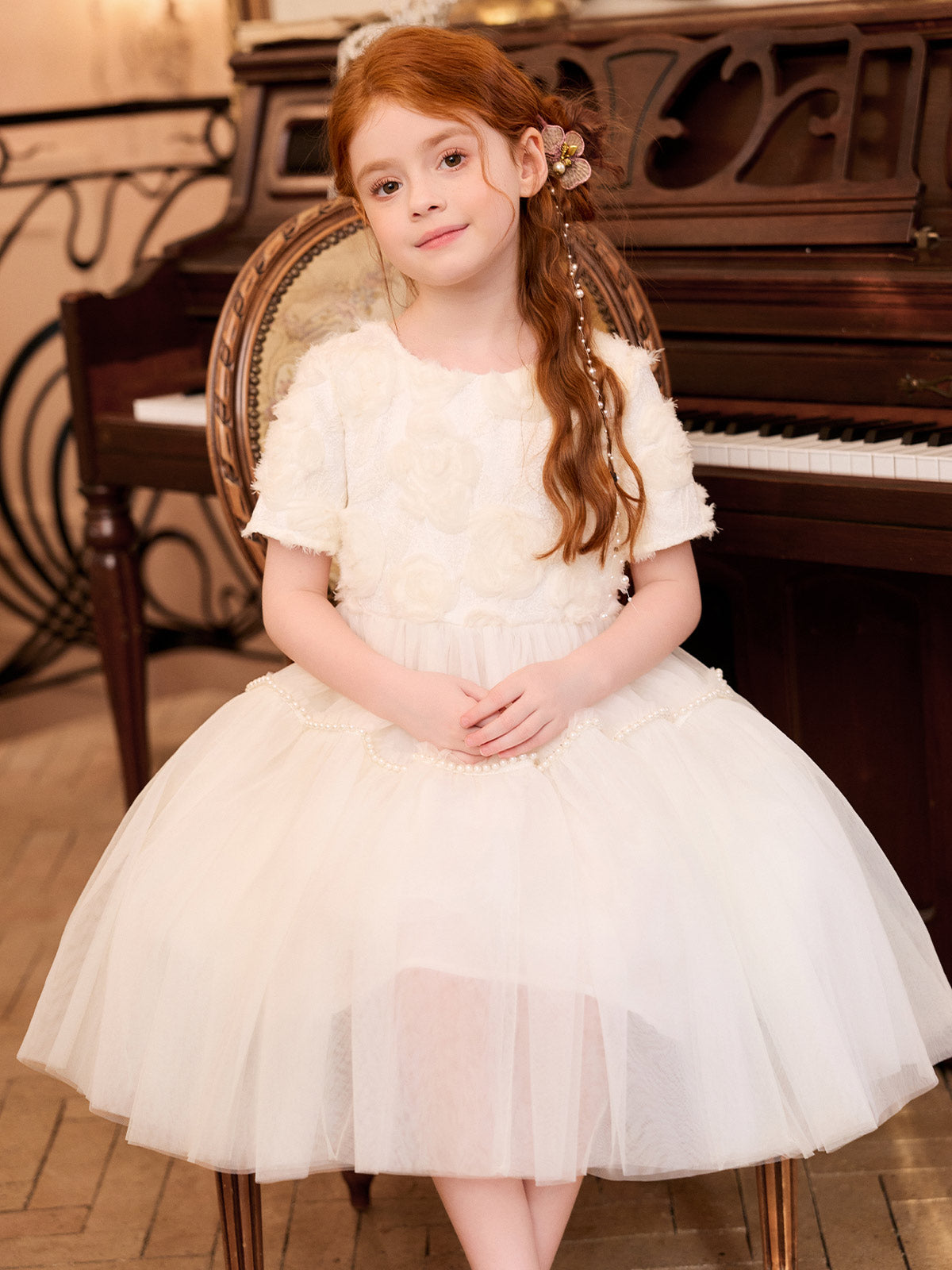 Seated model wearing the ivory rose dress without the cape